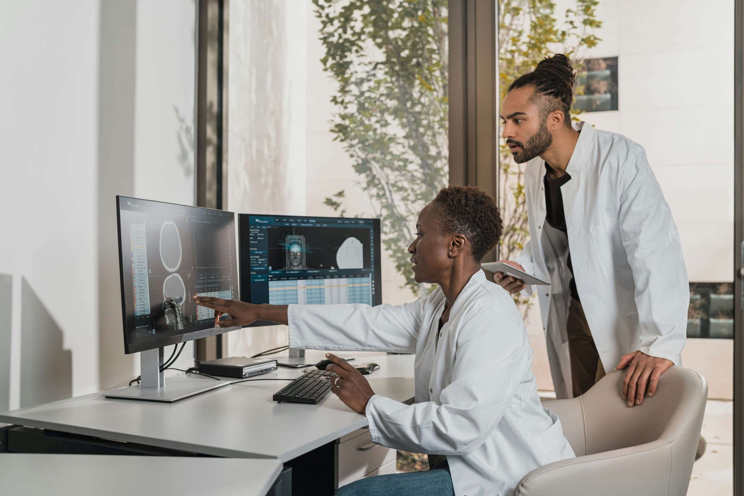 A doctor at a workstation, reading a patient's record on screen